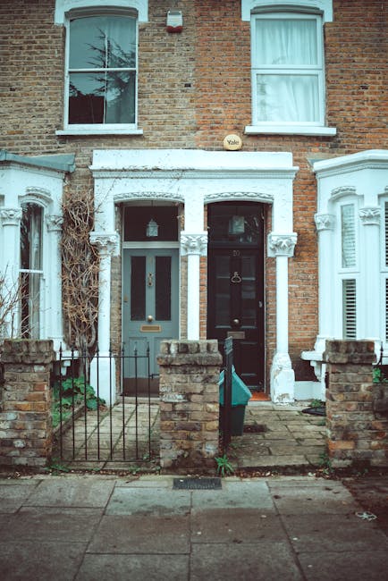A row of white Victorian-style terraced houses with decorative mouldings, large bay windows, and ornate black iron balconies. The houses have polished stone steps leading to entrance doors, and the fa